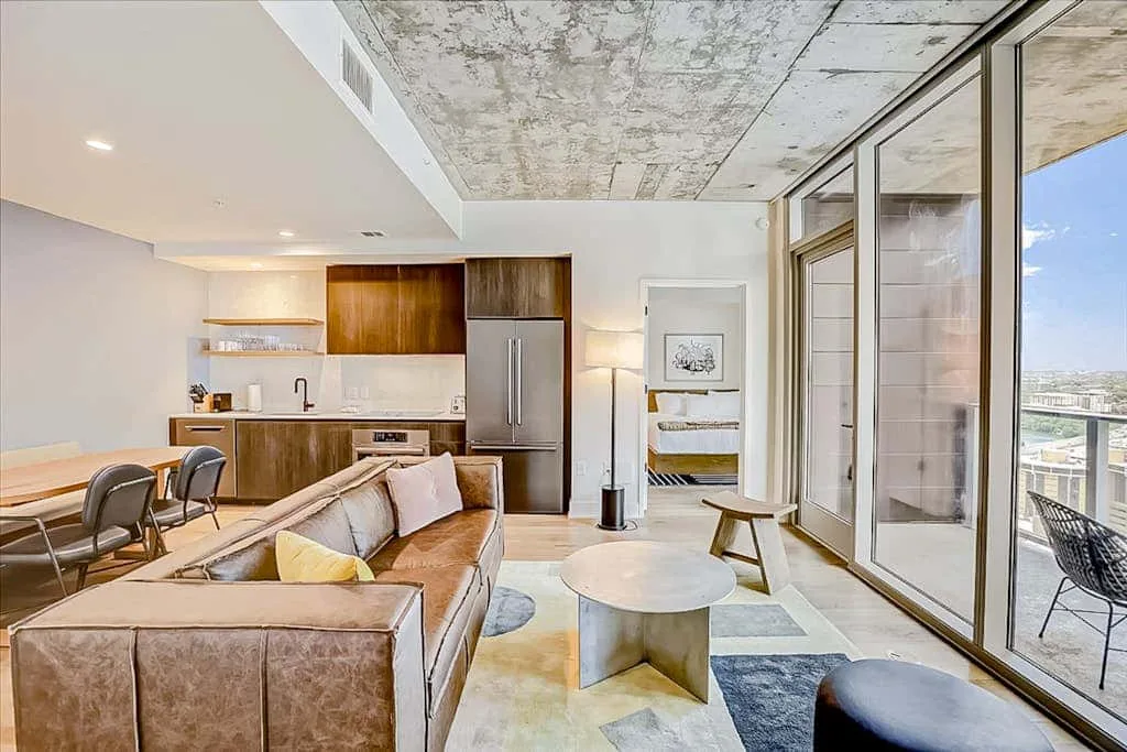Una sala de estar diáfana y moderna con cocina y grandes ventanas.