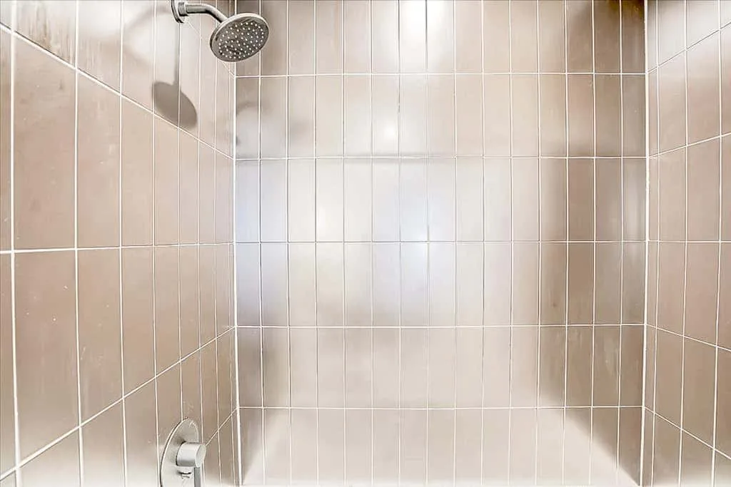 Una ducha revestida de azulejos con un cabezal montado en la pared.