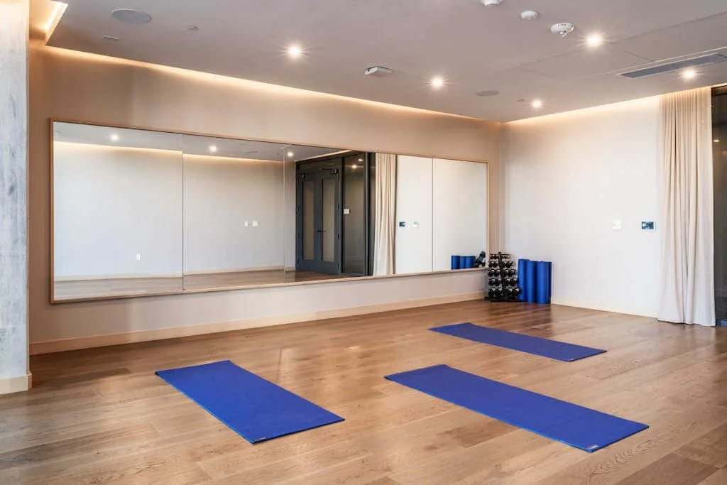 Una luminosa sala de ejercicio con colchonetas azules sobre el suelo de madera.