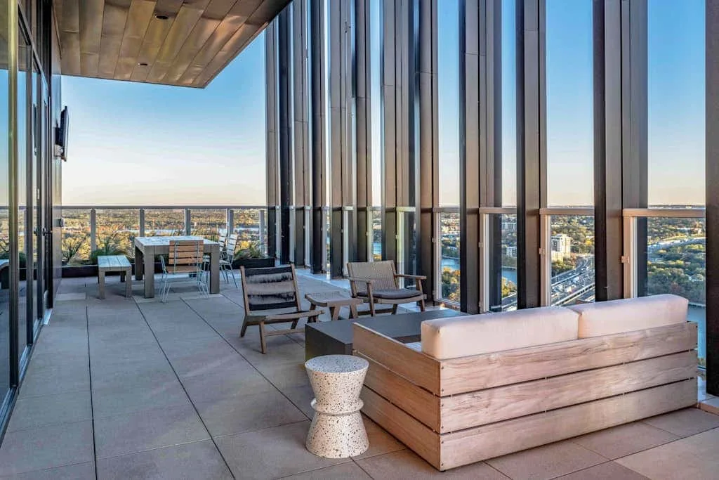 Una terraza amueblada con asientos ofrece vistas de la ciudad a través de ventanales.