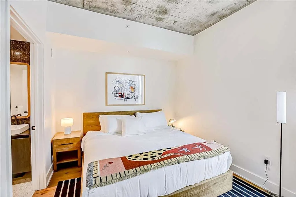 Un dormitorio con una cama grande, una mesita de noche y un cuadro sobre el cabecero.