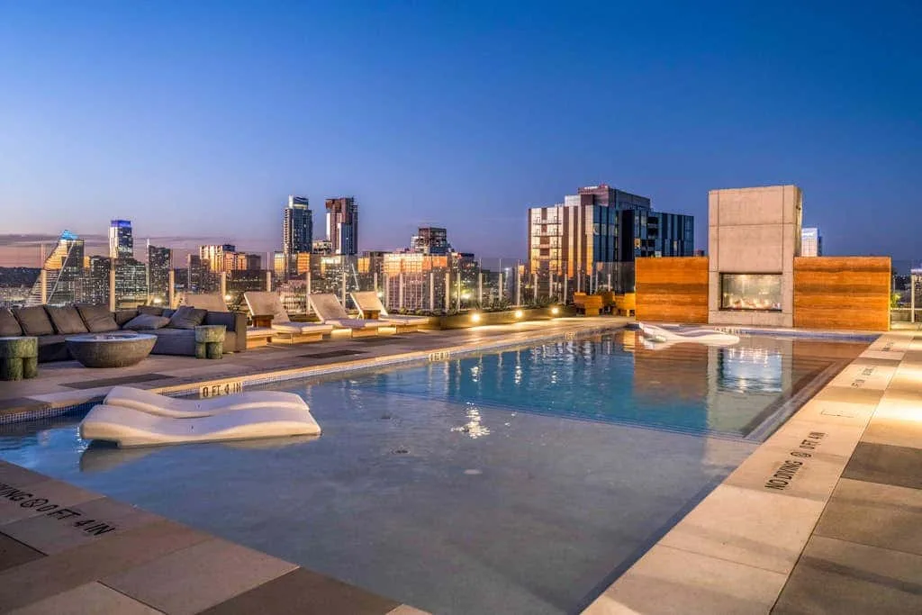 Una piscina en la azotea ofrece vistas del horizonte urbano al anochecer.