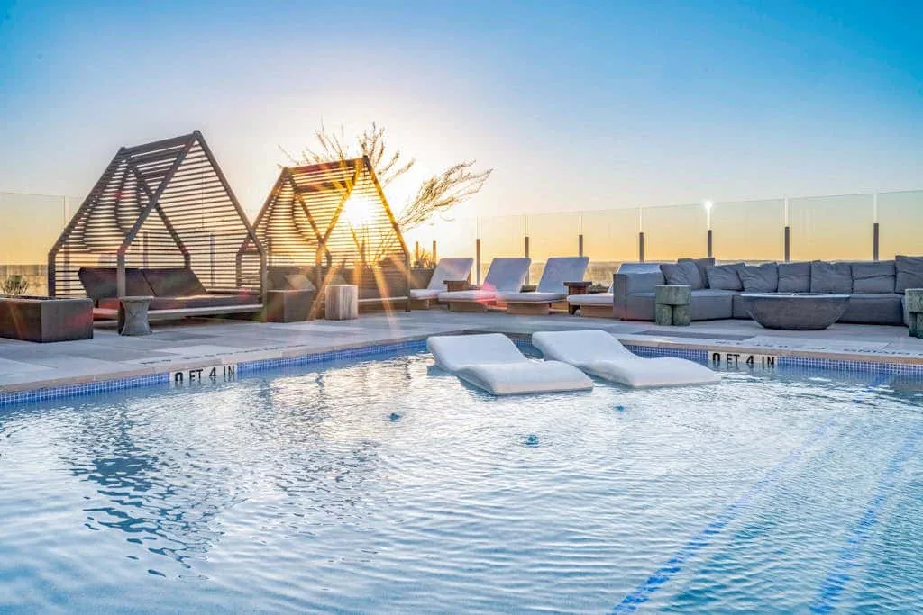 Una piscina en la azotea con tumbonas sumergidas y asientos junto a la terraza.