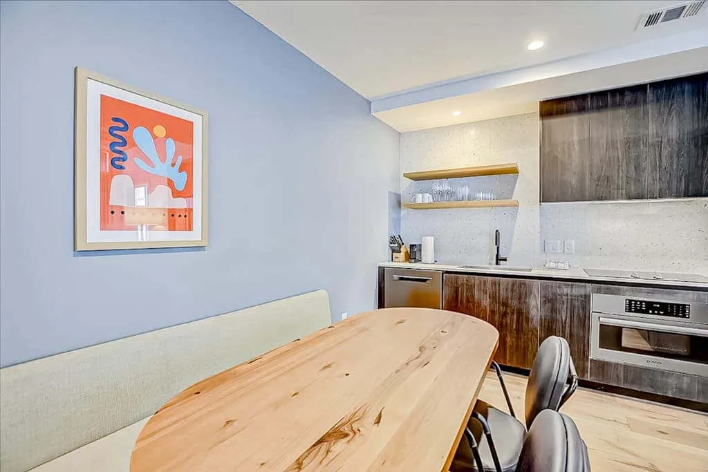 A dining area with a wooden table beside a compact kitchen.