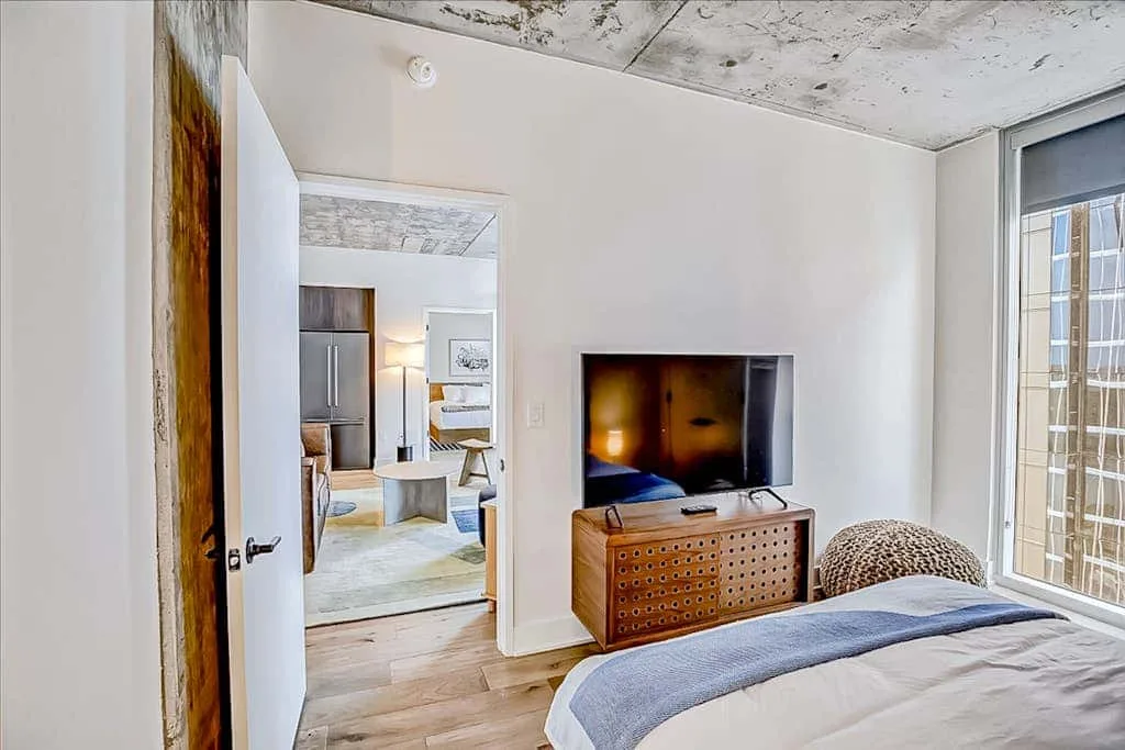 Un dormitorio con una cama, un televisor y una cómoda de madera.
