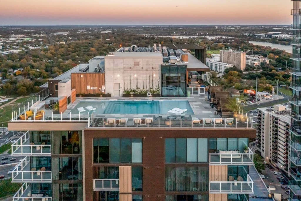 Una piscina y una zona de asientos en la azotea ofrecen vistas de la ciudad al atardecer.