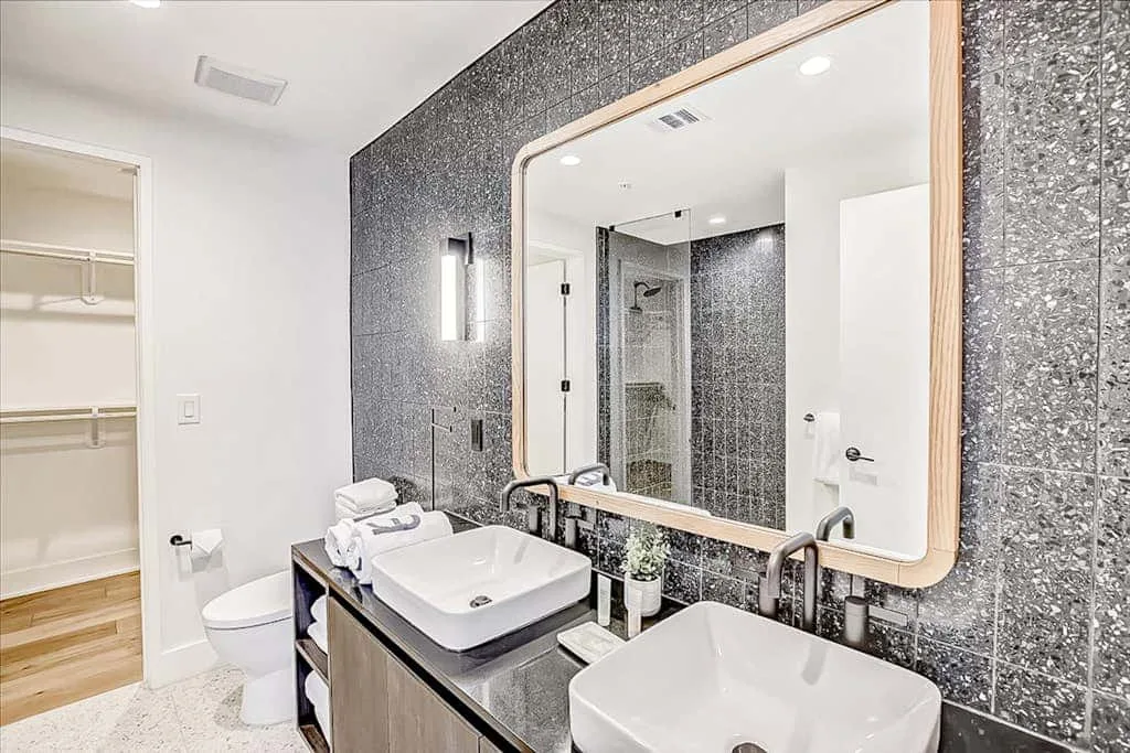 Un baño con dos lavabos, un espejo grande y una ducha de vidrio.