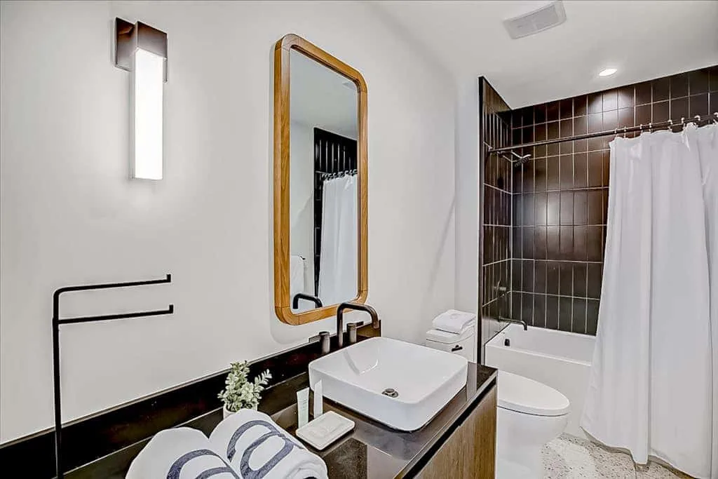 Un baño con lavabo, espejo, inodoro y ducha detrás de una cortina.