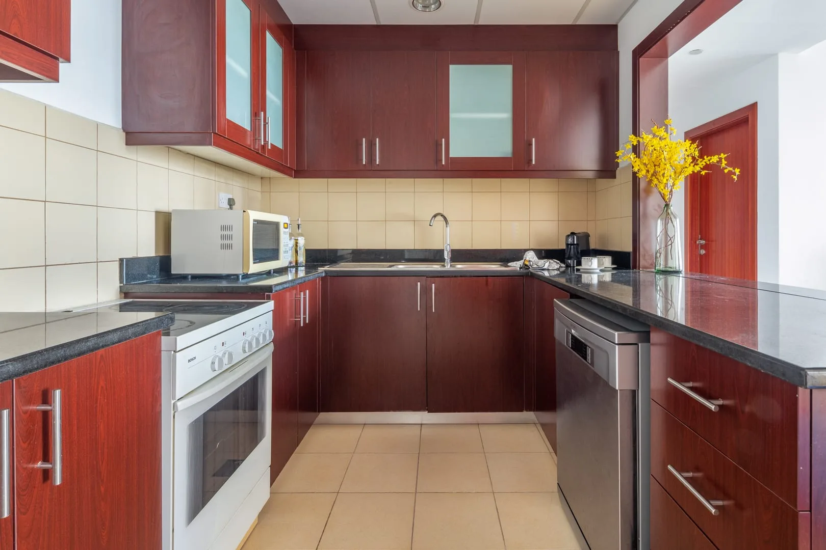 Una cocina con gabinetes de madera oscura, paredes de azulejos y una encimera central.