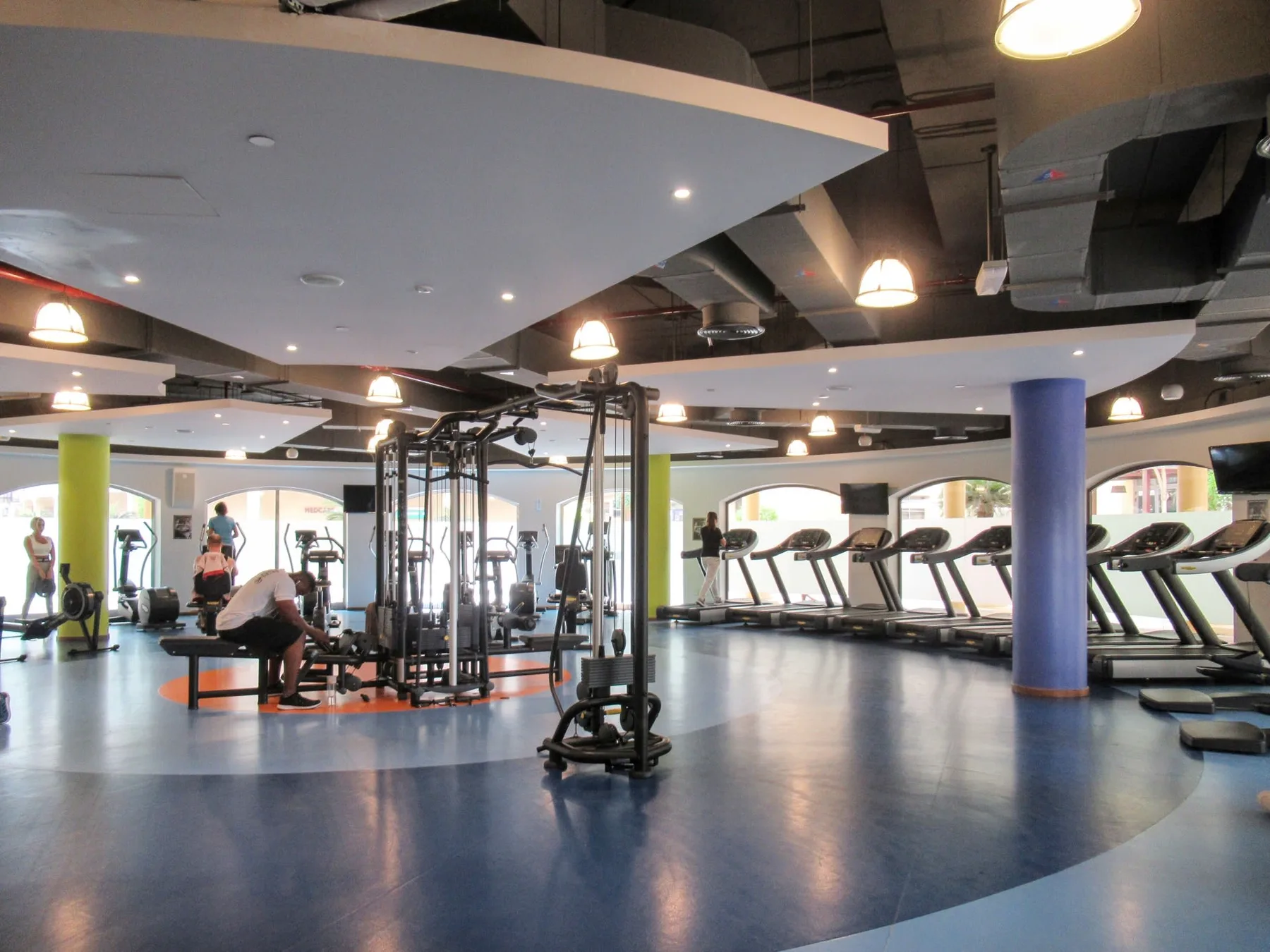Un gimnasio con máquinas de ejercicio y cintas de correr distribuidas en una sala abierta.