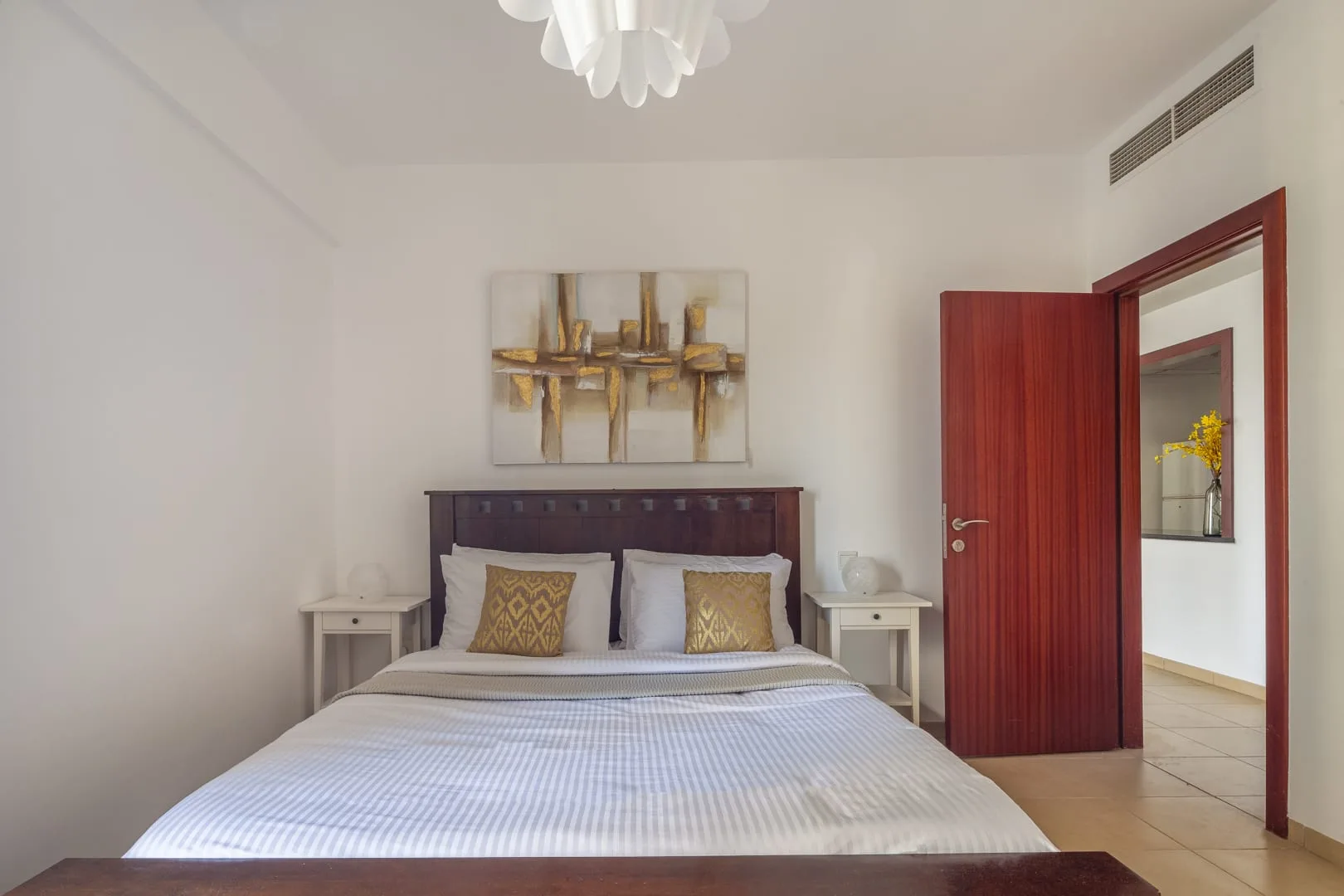 Un dormitorio con una cama, mesitas de noche y una puerta abierta.