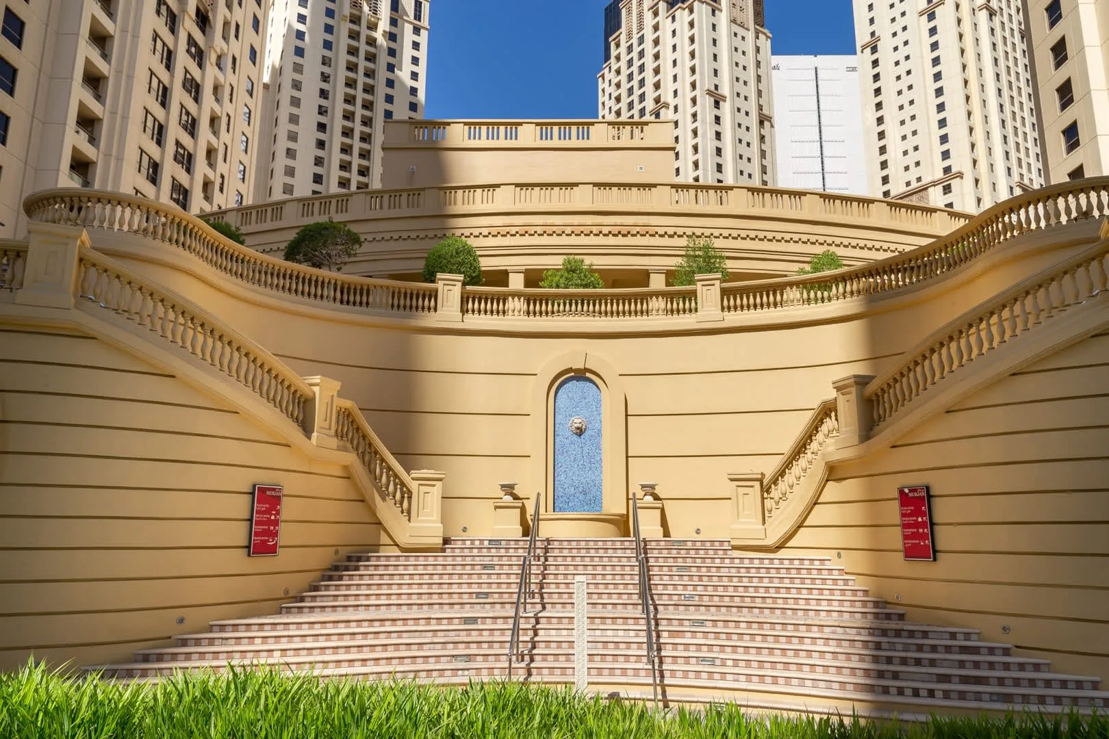Una amplia escalera exterior asciende entre muros curvos bajo edificios altos de apartamentos.