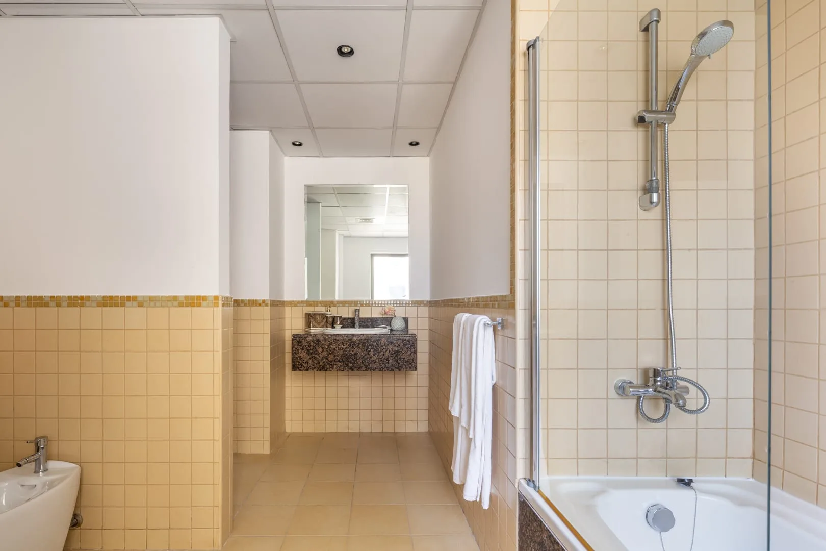 Un baño con azulejos, ducha y lavabo.