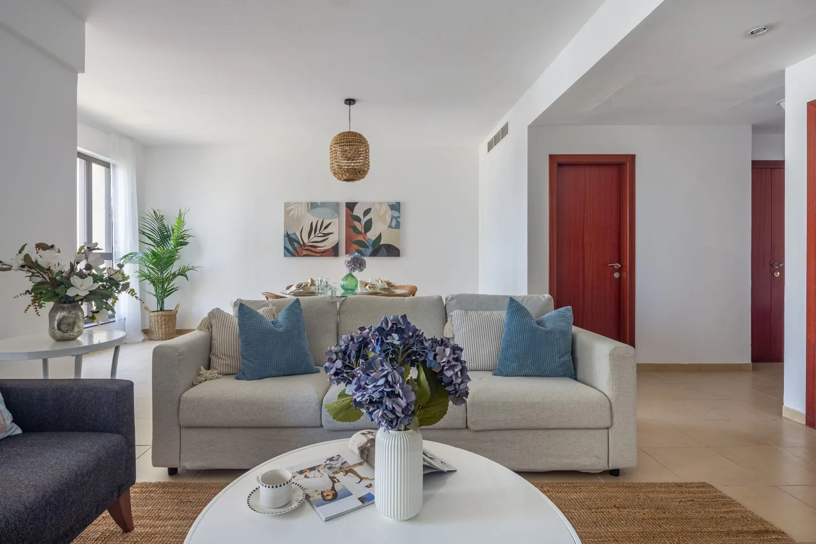 Una sala luminosa con asientos, una mesa de centro redonda y arreglos florales.