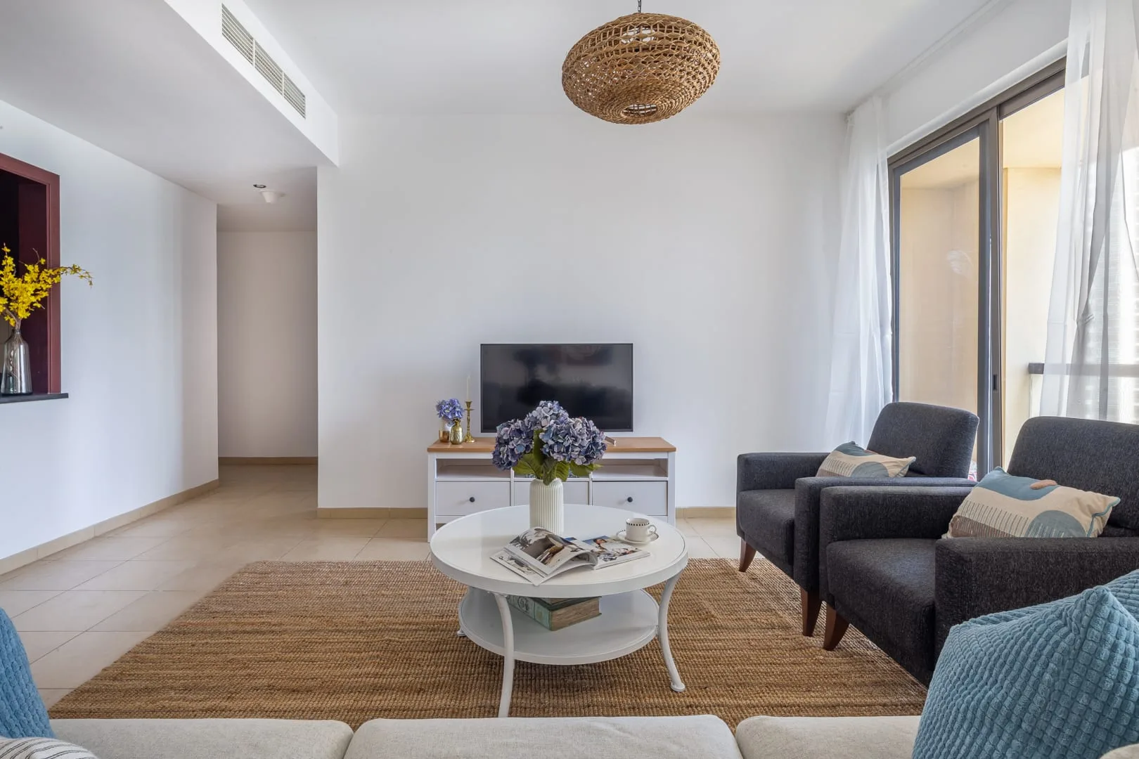 Una sala luminosa con asientos alrededor de una mesa de centro y un televisor.
