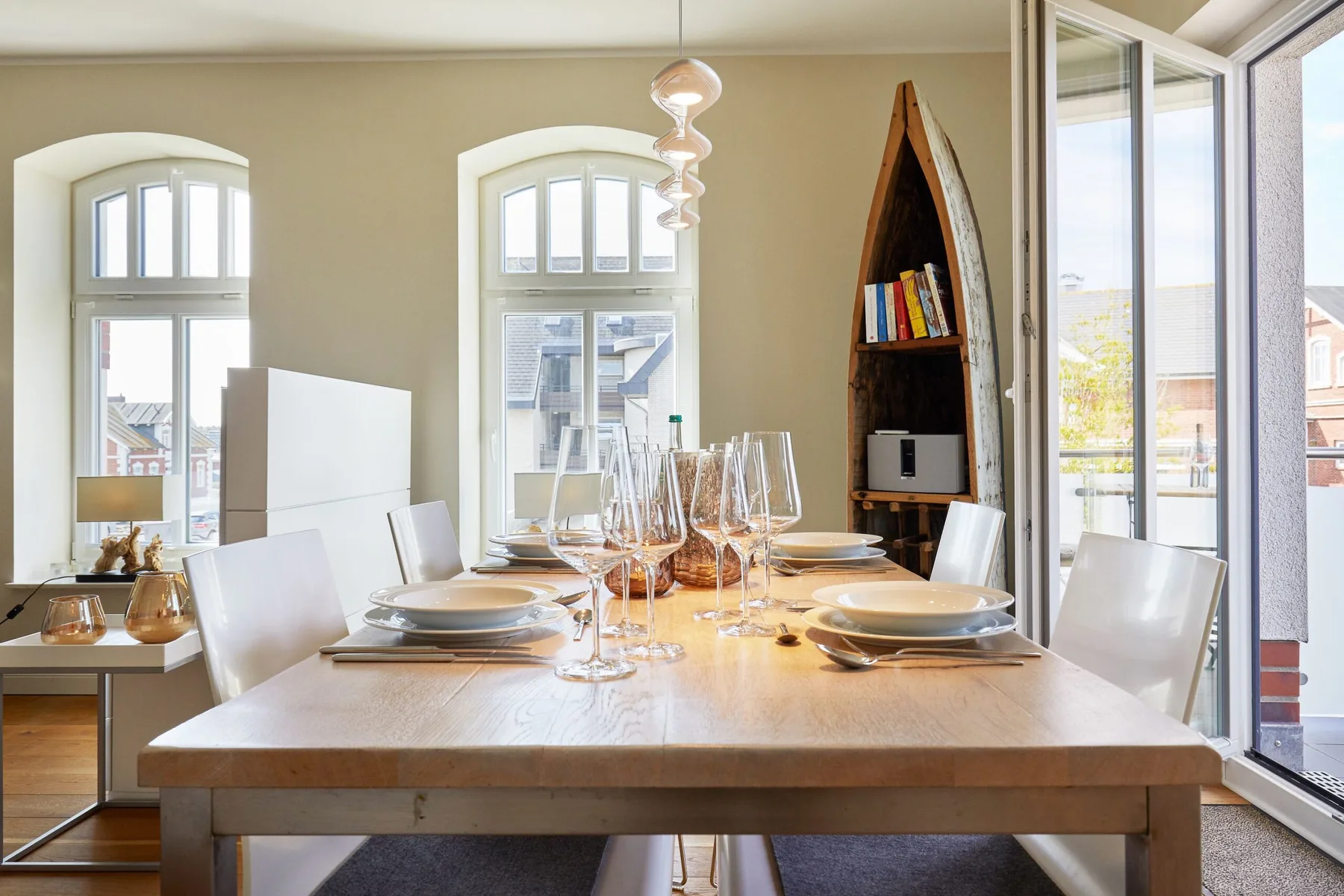 Comedor con una mesa puesta junto a ventanales altos y estanterías empotradas.