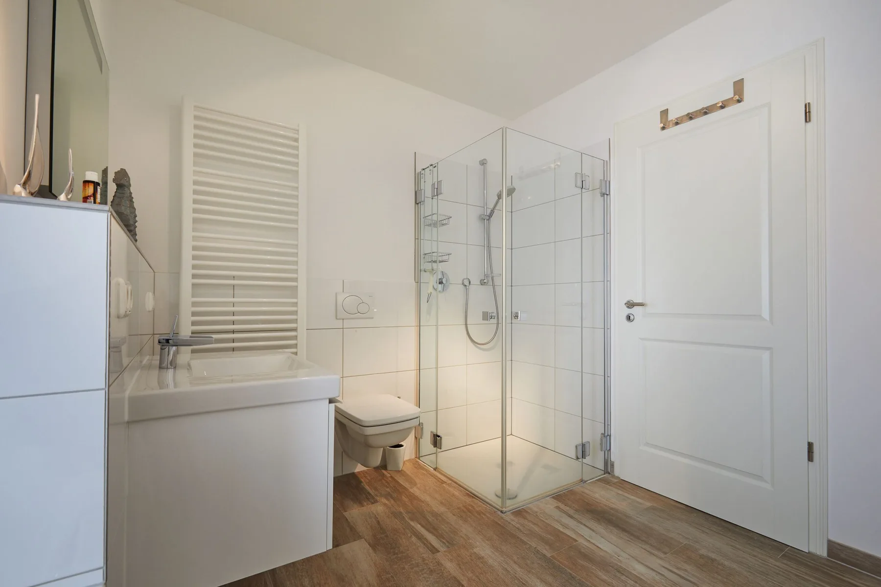 Un baño luminoso con ducha de vidrio, lavabo e inodoro.