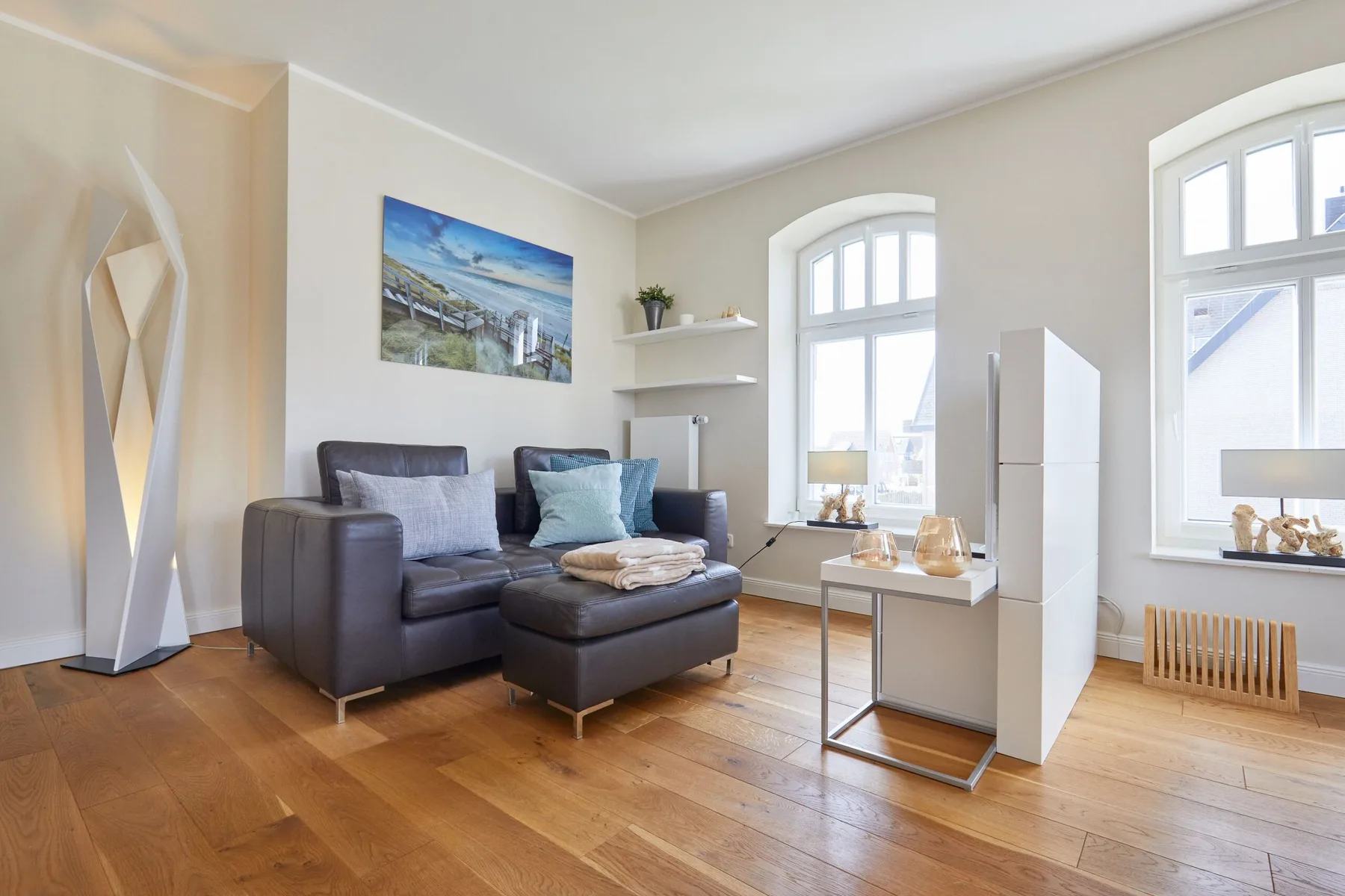 Una sala luminosa con un sofá seccional y ventanas grandes.