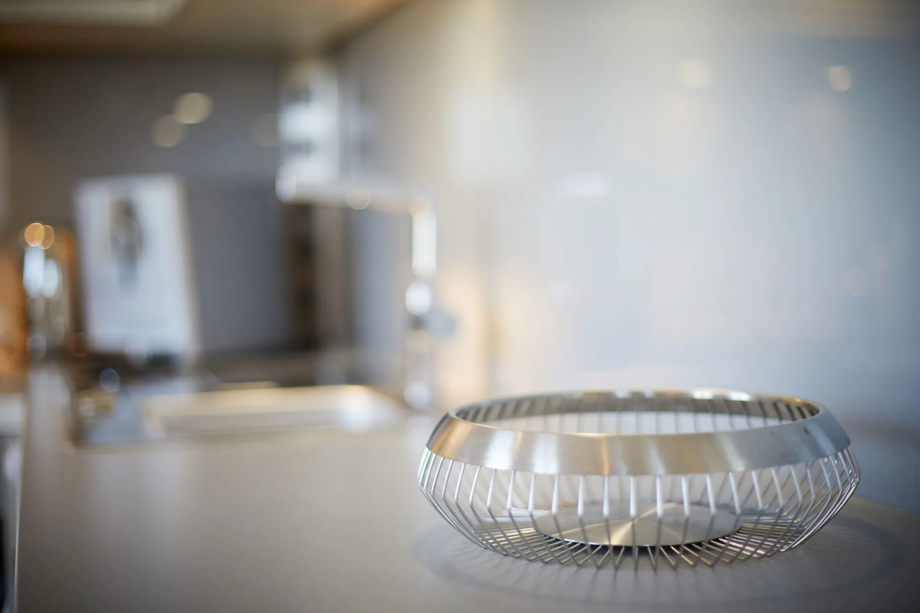 Un lavabo de baño con una cesta metálica sobre la encimera.
