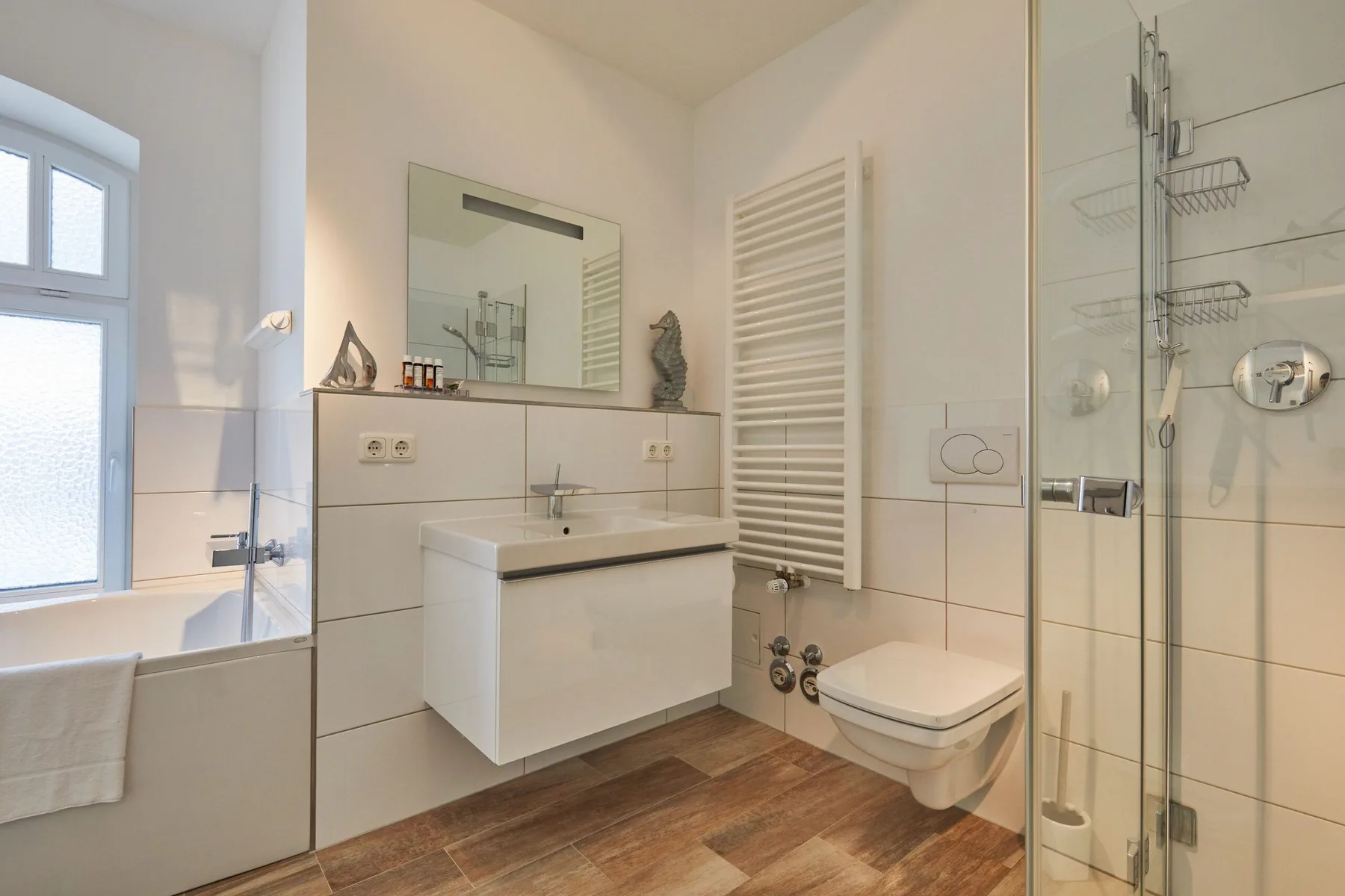 Un baño luminoso con bañera, lavabo, inodoro y ducha de vidrio.