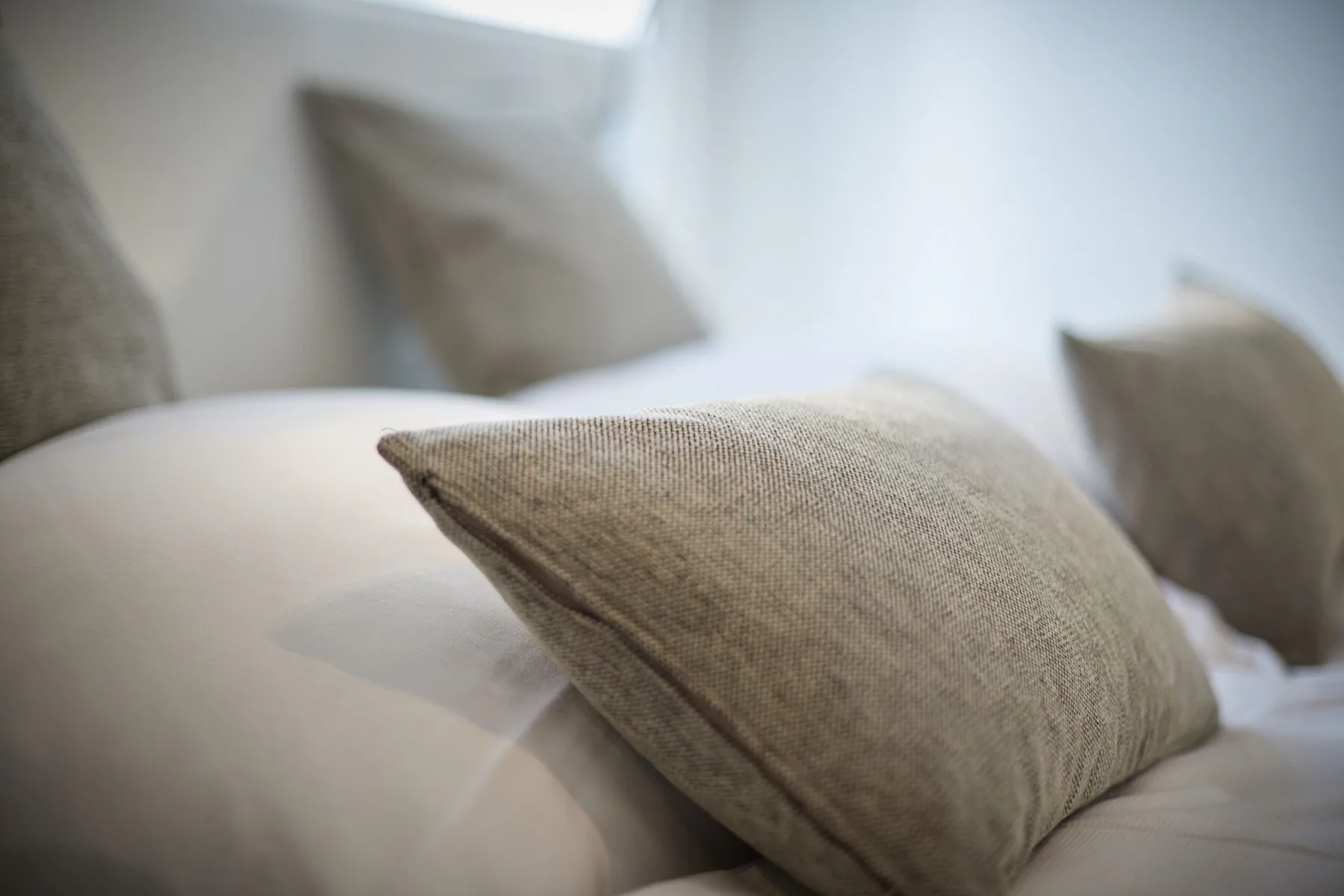 Dormitorio con almohadas neutras sobre una cama.