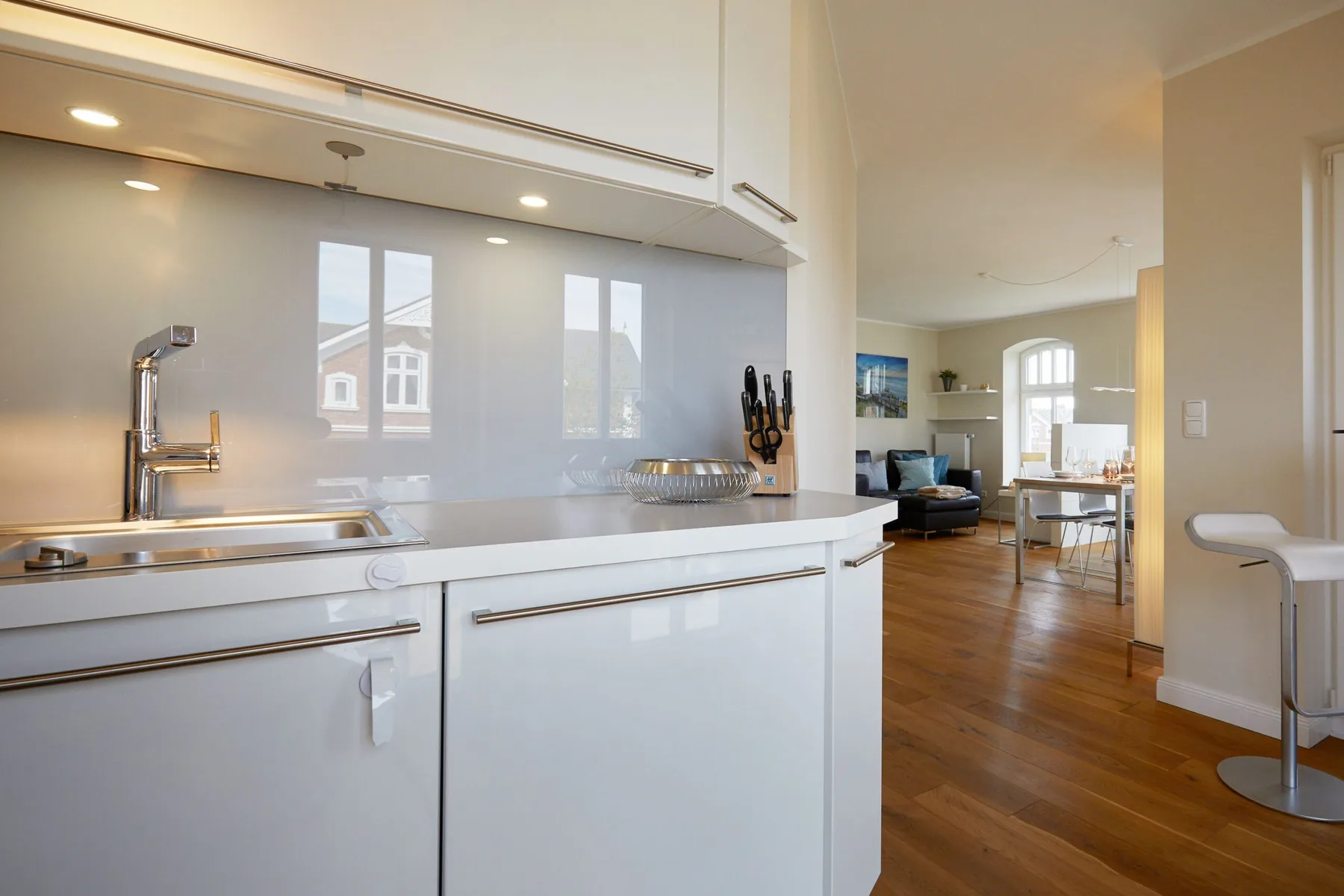 Una cocina luminosa se abre a una sala de estar y comedor con piso de madera.