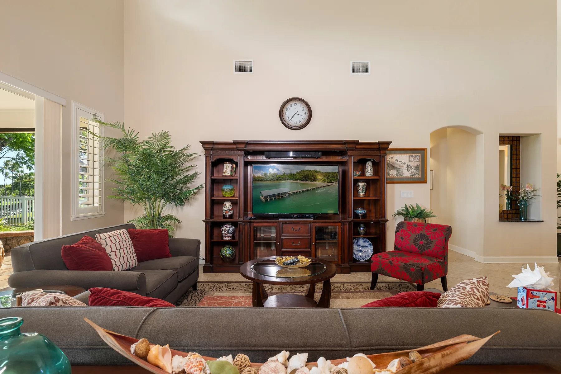 Una sala de estar con asientos dispuestos alrededor de un televisor y un mueble de entretenimiento de madera.