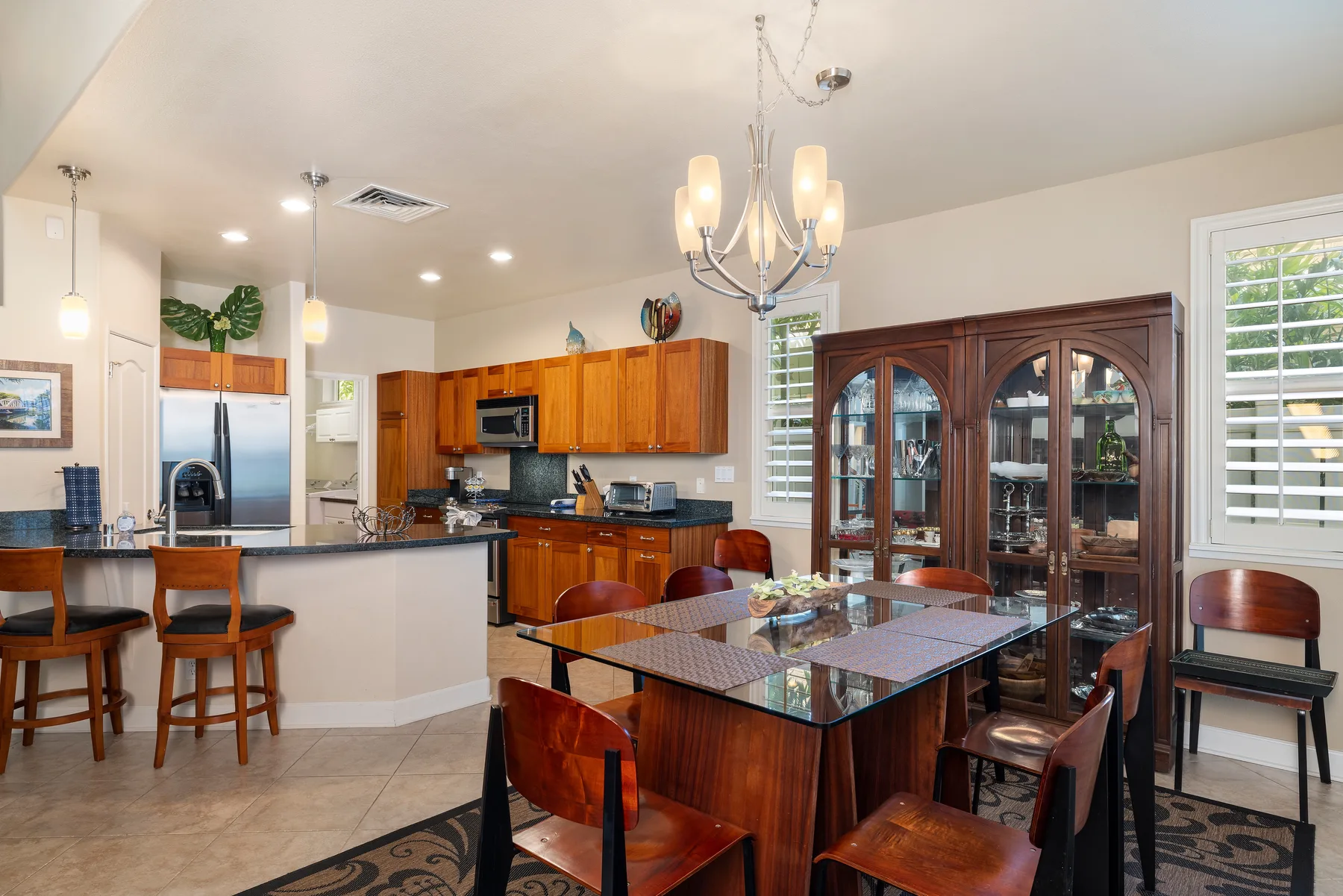 Una cocina abierta y zona de comedor con una mesa de vidrio y gabinetes de madera.