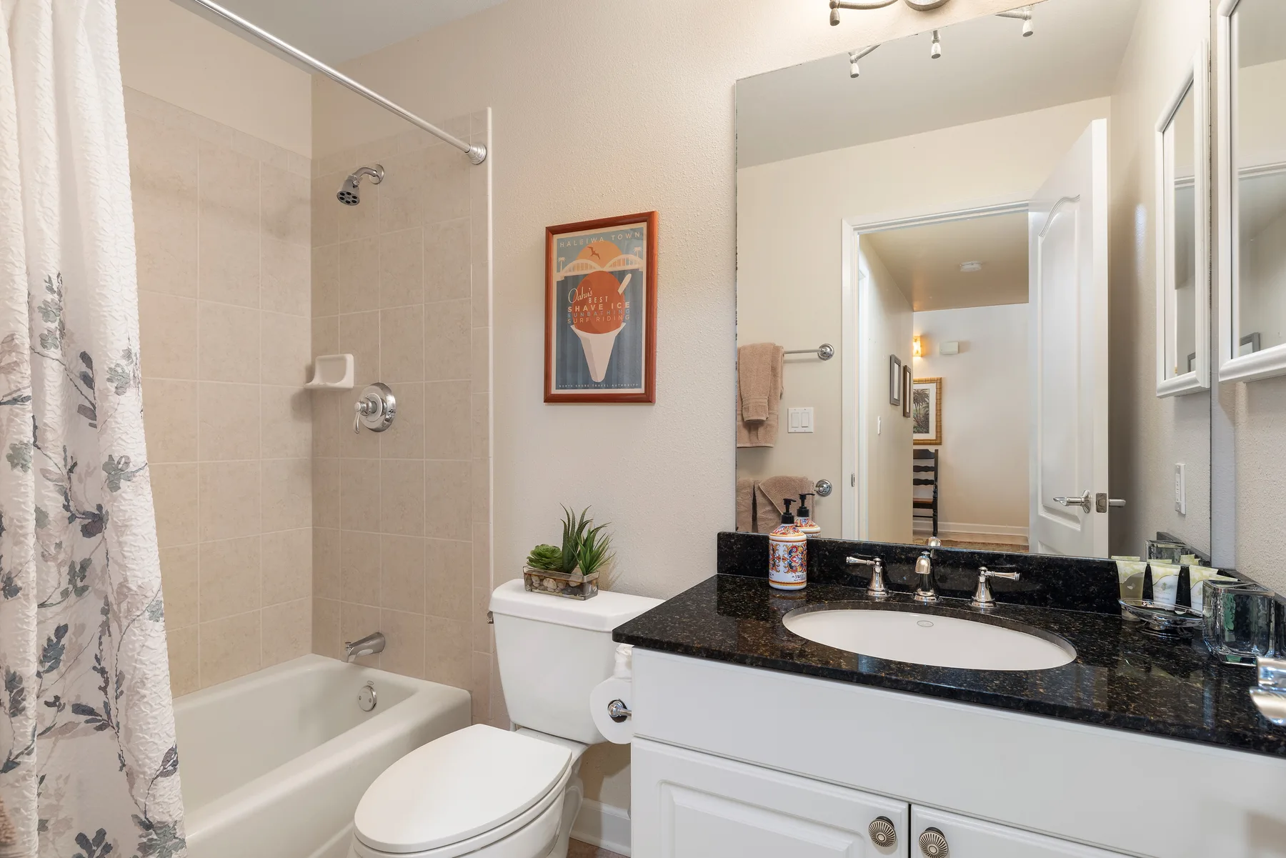 Un baño con bañera, inodoro y lavabo bajo un espejo amplio.