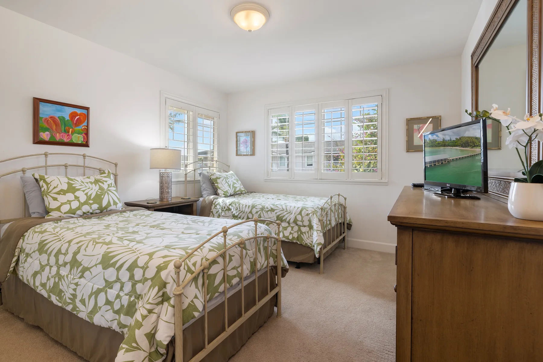 Un dormitorio con dos camas vestidas con ropa de cama floral verde y blanca.