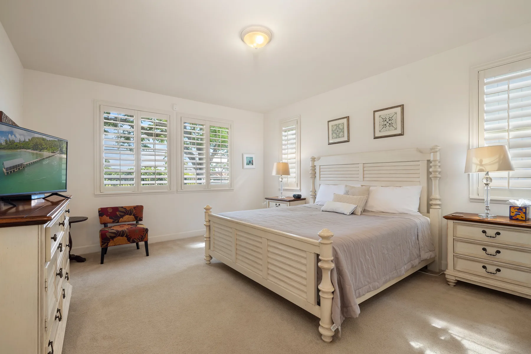 Un dormitorio luminoso con una cama grande y ventanas con persianas.