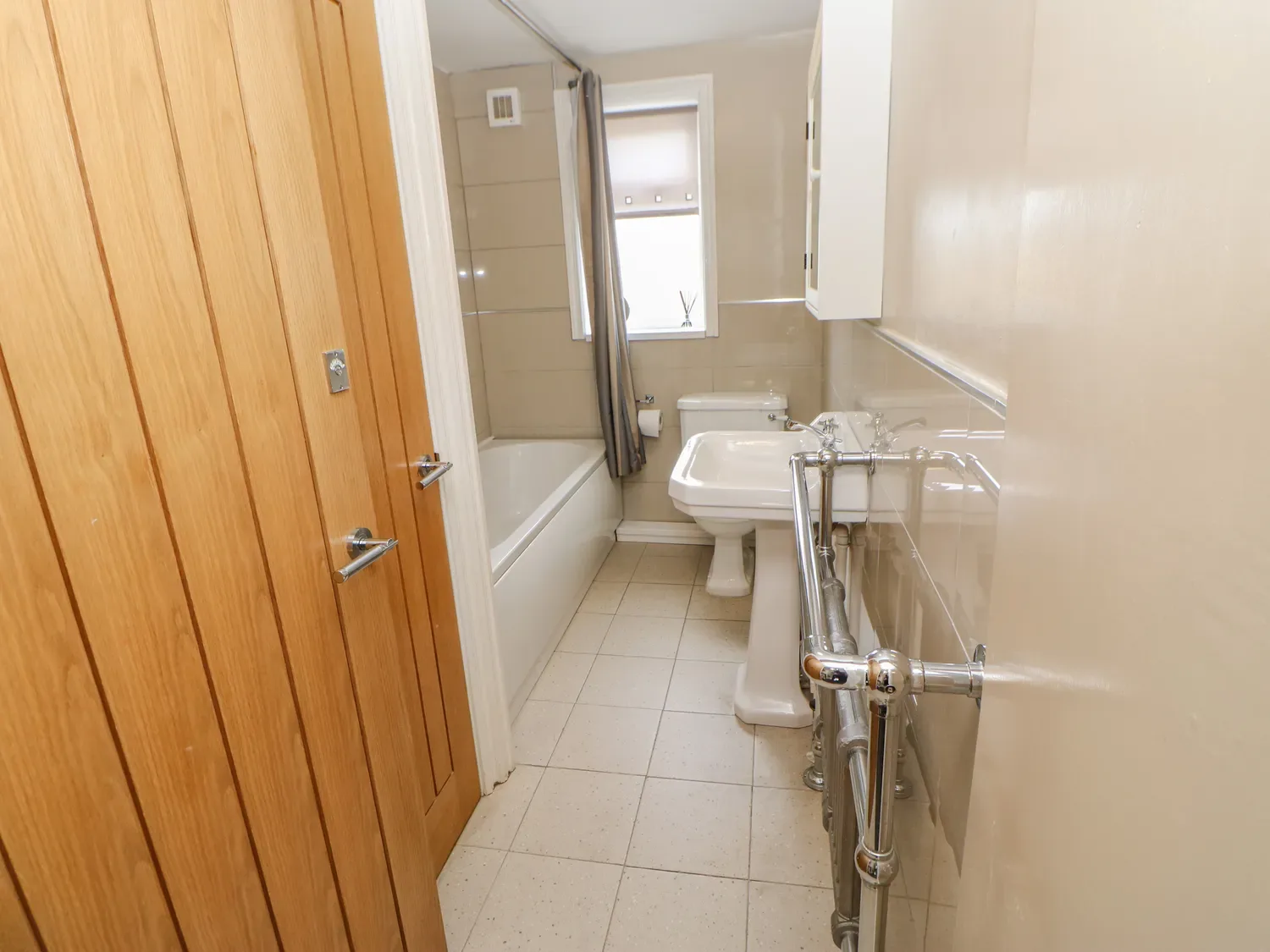 Un baño con bañera, lavabo e inodoro junto a una puerta de madera.