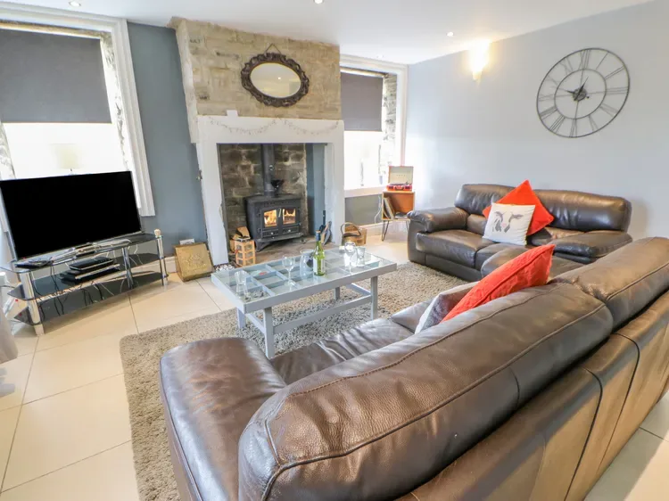 A living room with leather seating, a glass coffee table, and a fireplace.