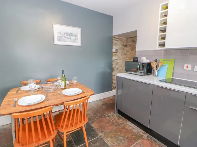 Comedor con mesa y sillas de madera junto a una cocina moderna.