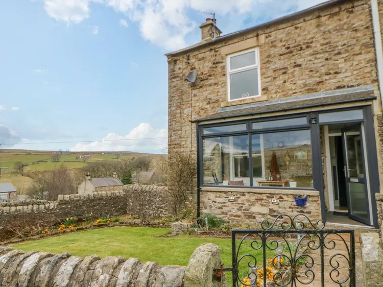 A stone house opens onto a small garden with a wide glazed window.