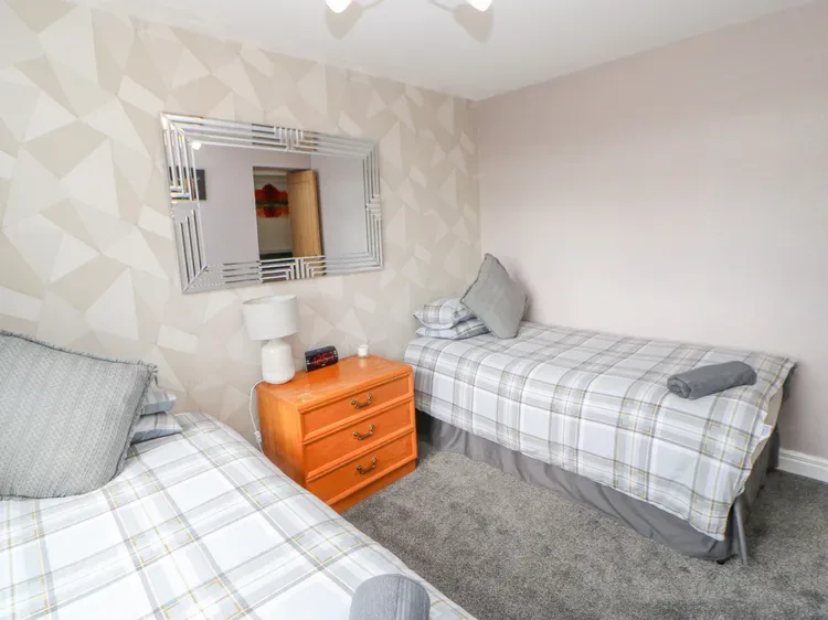 Un dormitorio con dos camas a cuadros y una cómoda naranja junto a ellas.
