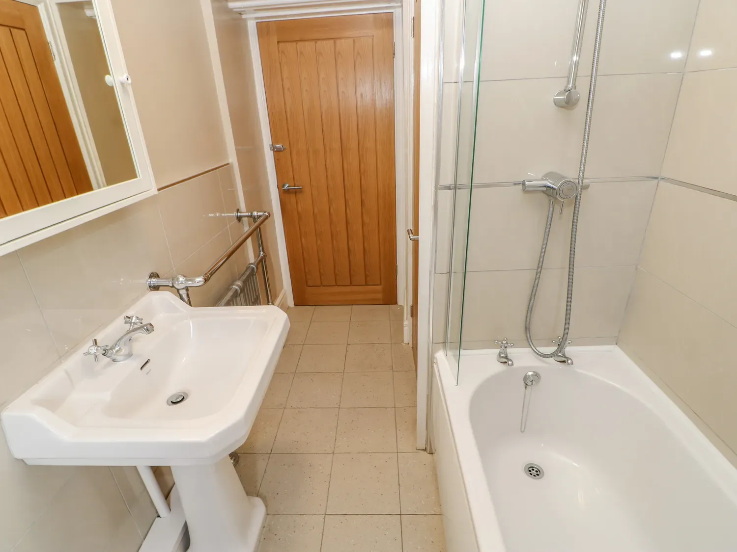 Un baño con un lavabo de pedestal y una bañera con ducha.