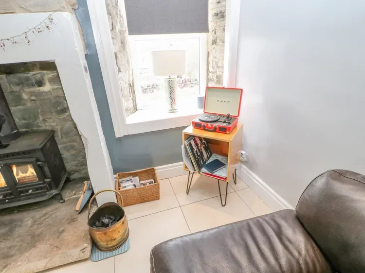 A living room with a record player on a small stand beside a window.