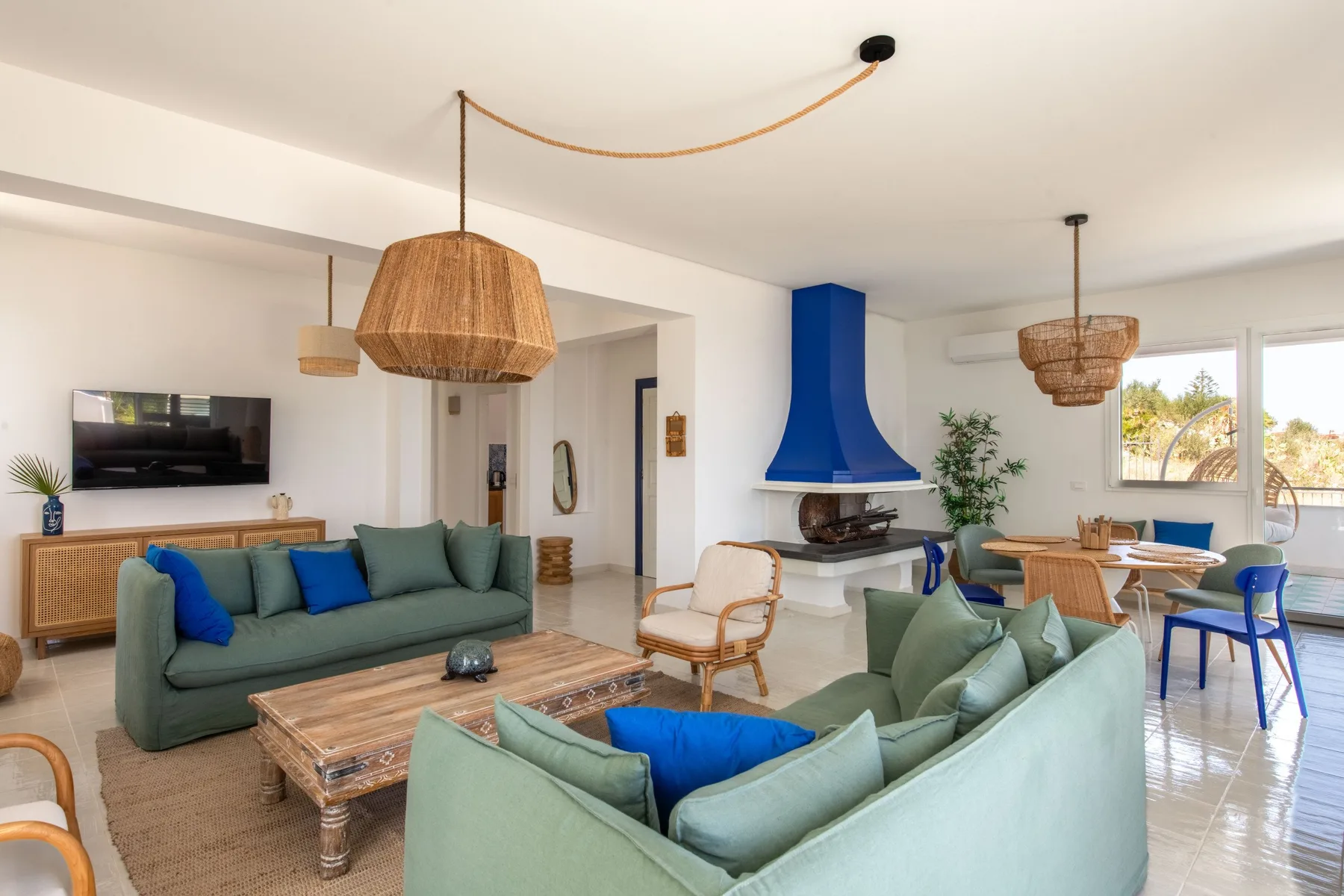 A bright living room with green seating and a blue fireplace.