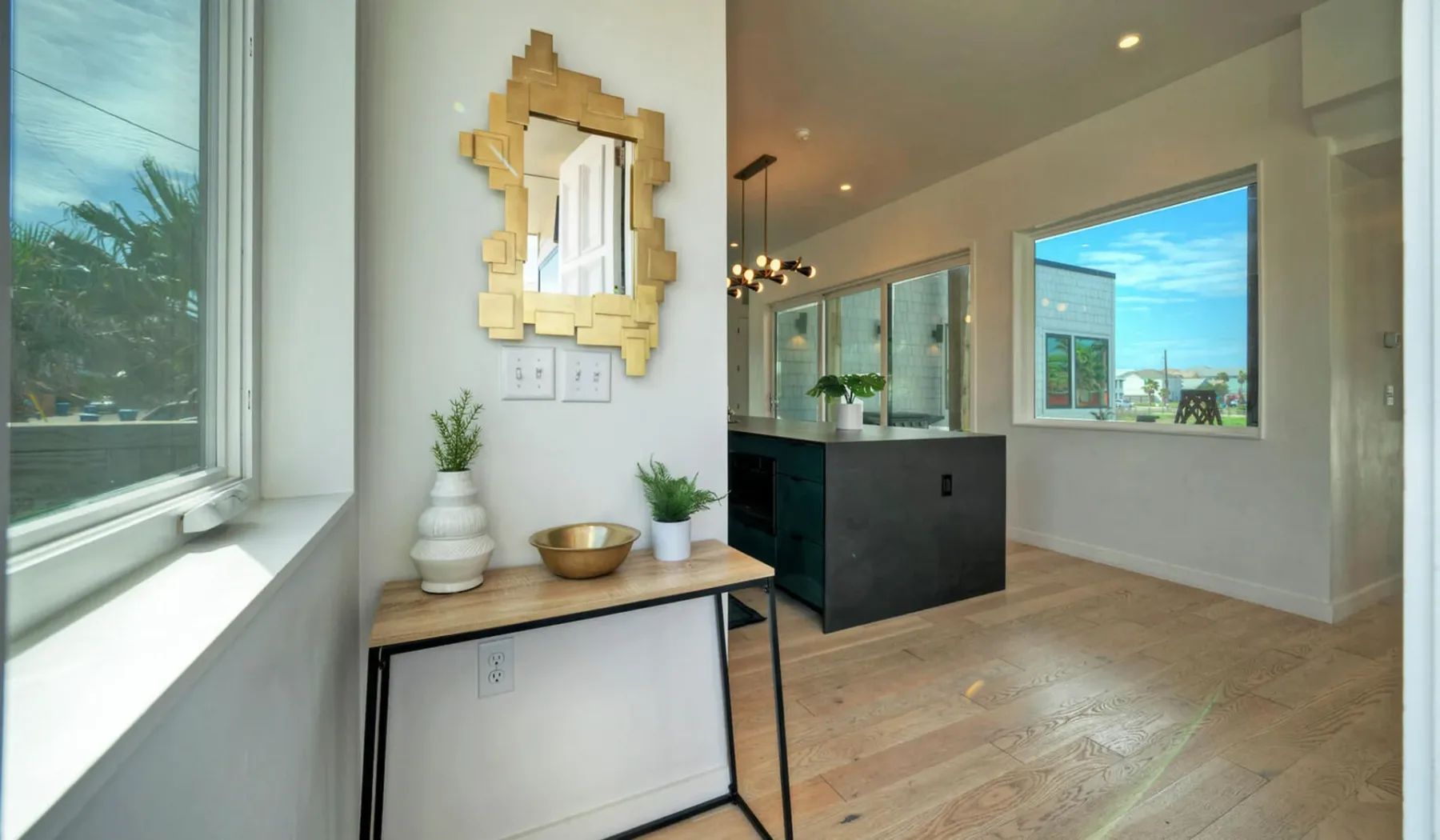 A bright modern interior with a console table and a dark kitchen island.