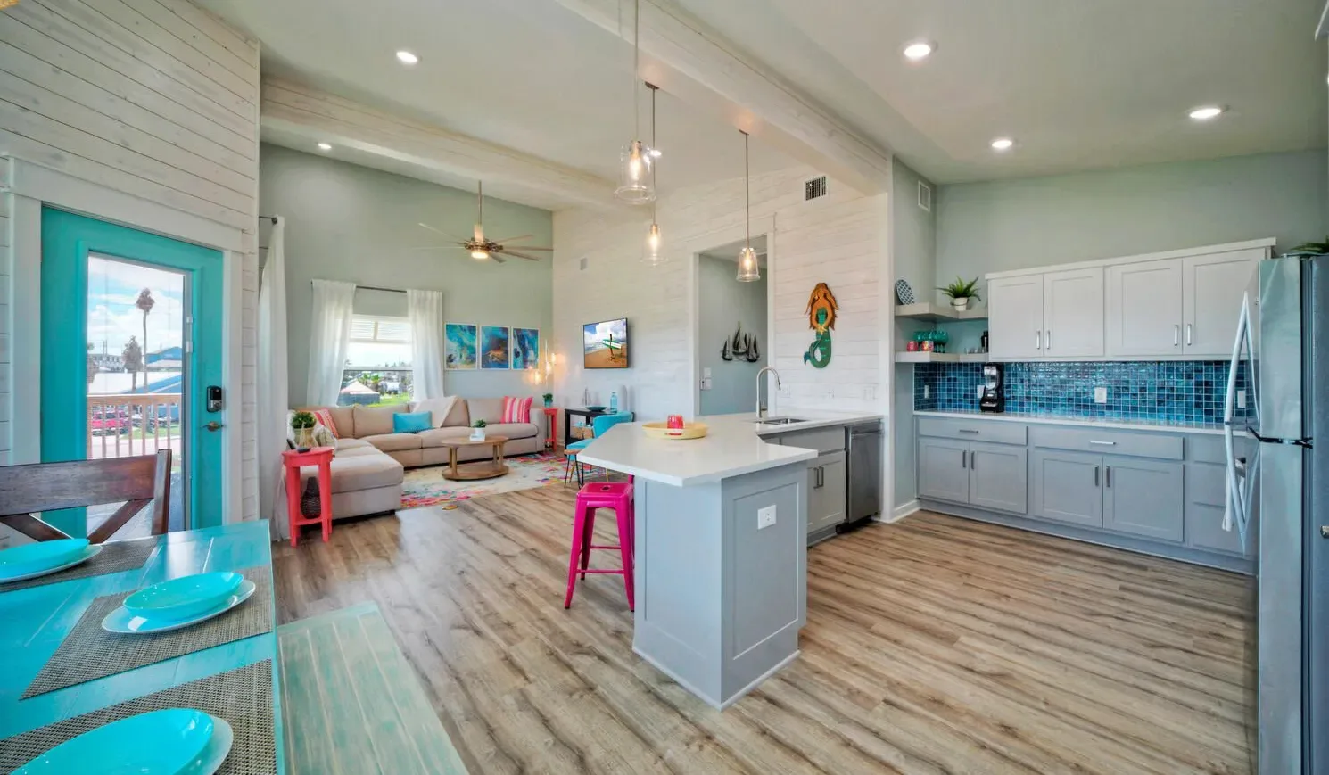 An open-plan kitchen and living area with a central island and colorful seating.
