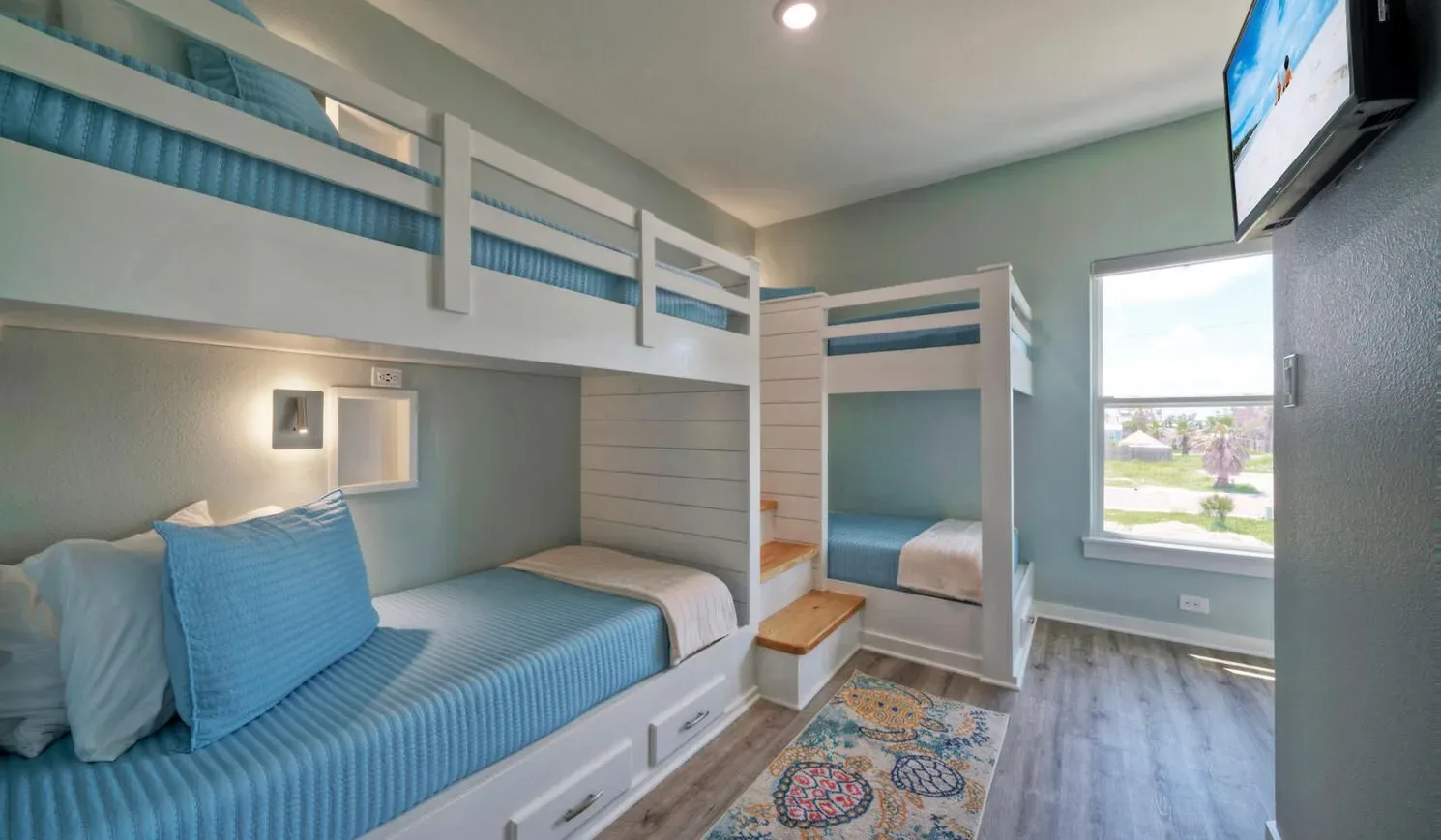 A bedroom with built-in bunk beds, blue bedding, and a window.