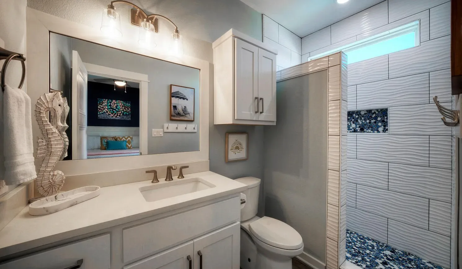 A bathroom with a vanity, mirror, toilet, and tiled shower.