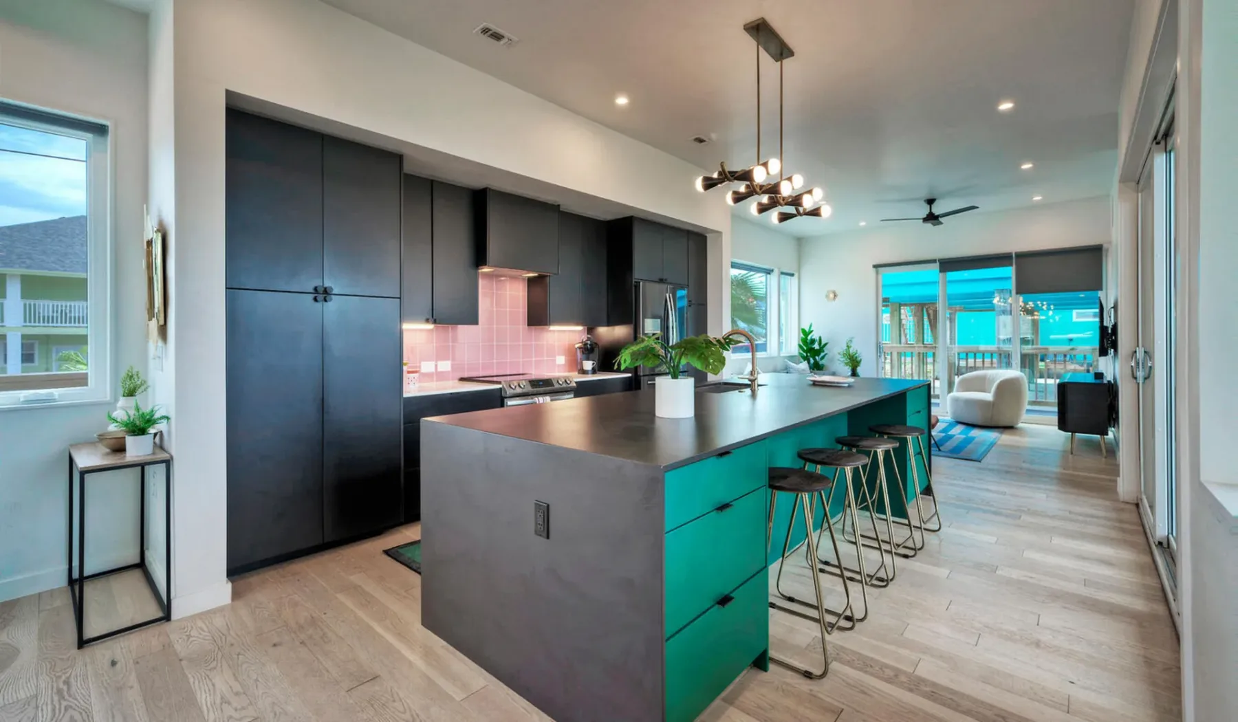 A modern kitchen with a large island and bar seating opens into a bright living area.