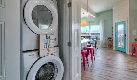 A laundry area with a stacked washer and dryer opens onto a dining space.