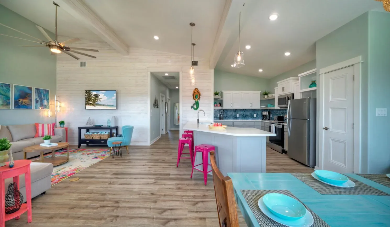 An open-plan living room and kitchen with a central island and colorful seating.