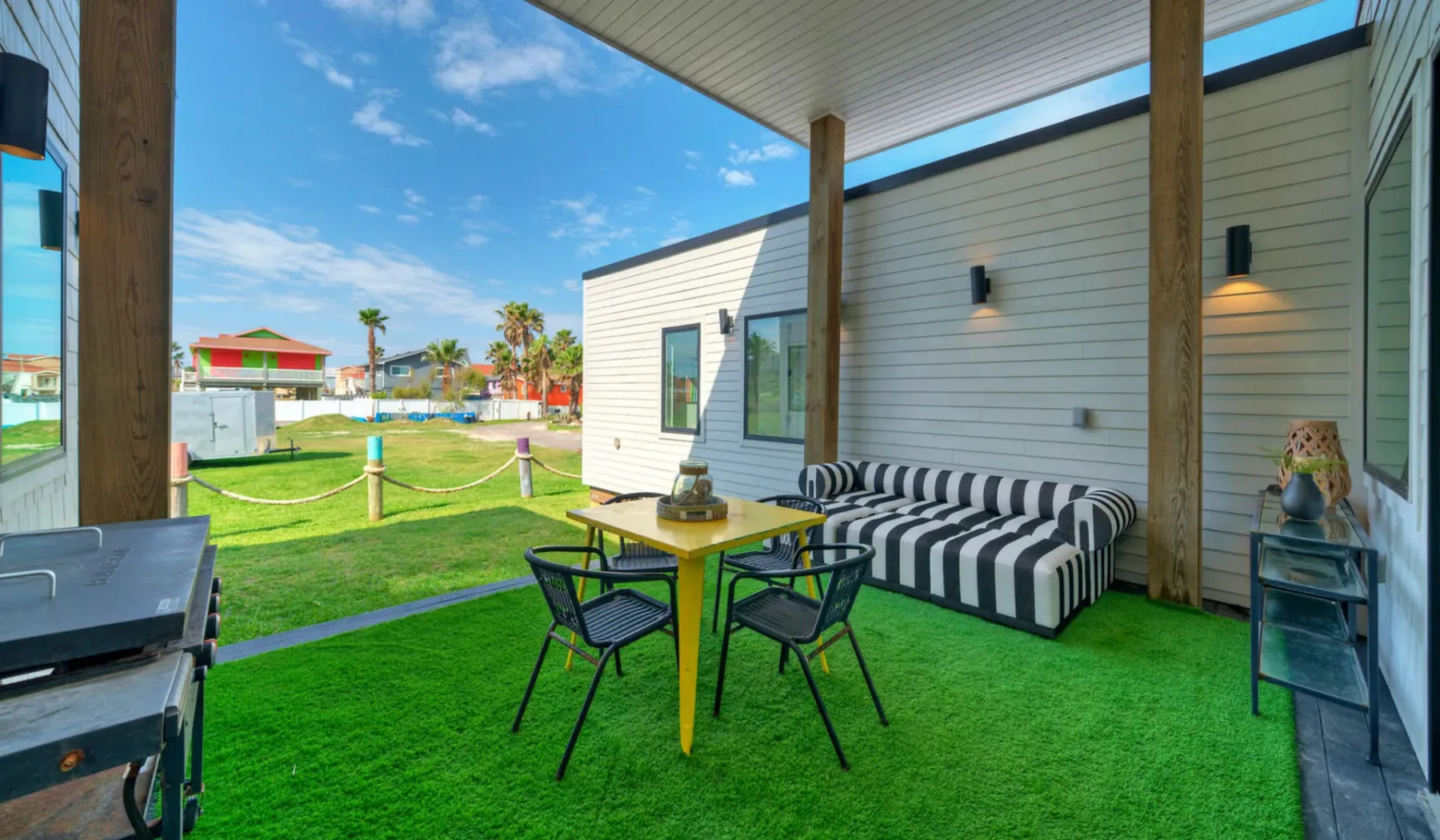 A covered outdoor seating area with a table and striped cushioned bench.