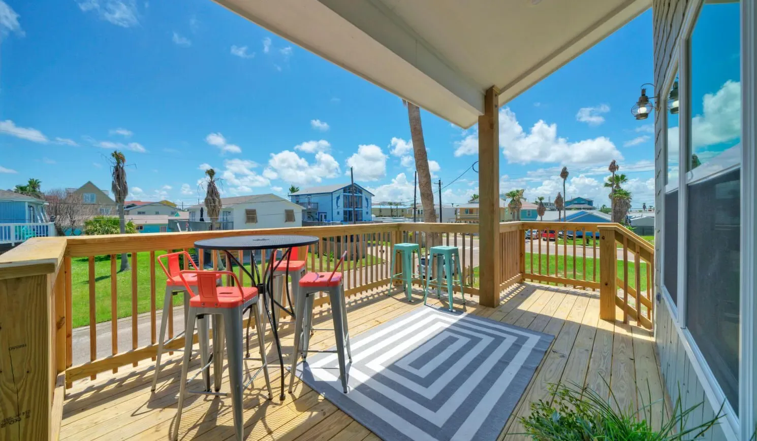 A covered wooden deck has a table and seating overlooking a grassy yard.
