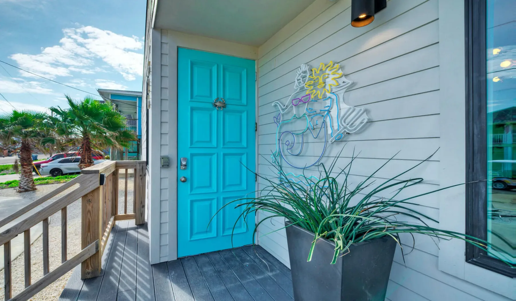 An outdoor entry porch with a turquoise door and a large potted plant.