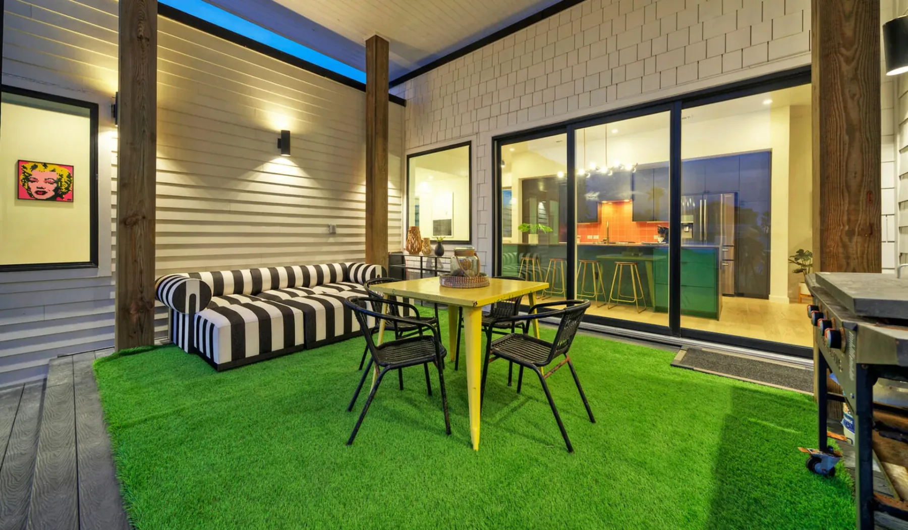 An outdoor dining area with a table and seating beside large glass doors.